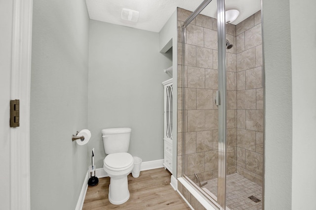 bathroom featuring hardwood / wood-style floors, a shower with door, and toilet