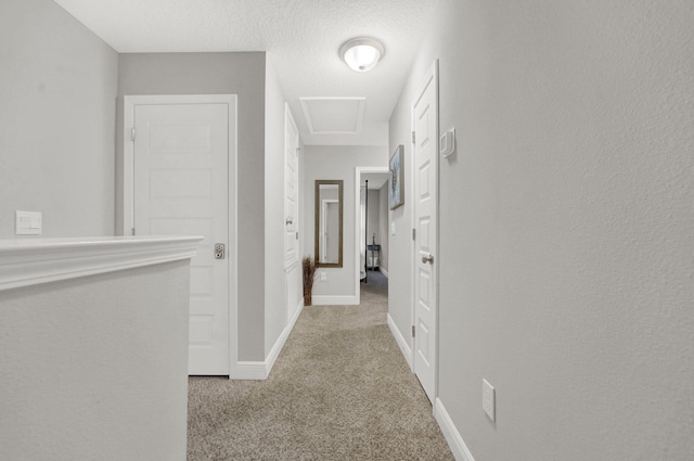 hall with light colored carpet and a textured ceiling