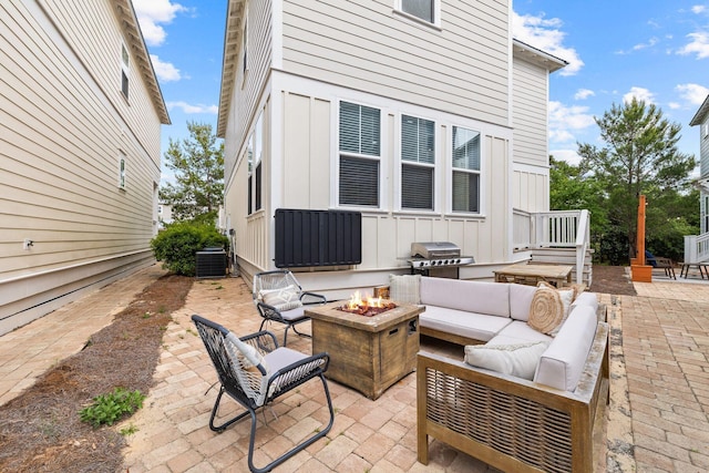 view of patio with area for grilling, an outdoor living space with a fire pit, and central air condition unit