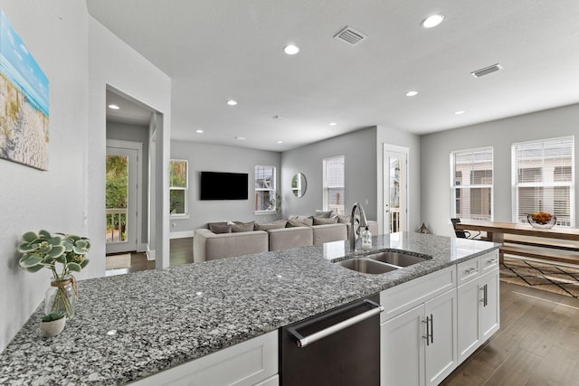 kitchen with sink, dishwasher, white cabinets, dark hardwood / wood-style flooring, and dark stone counters