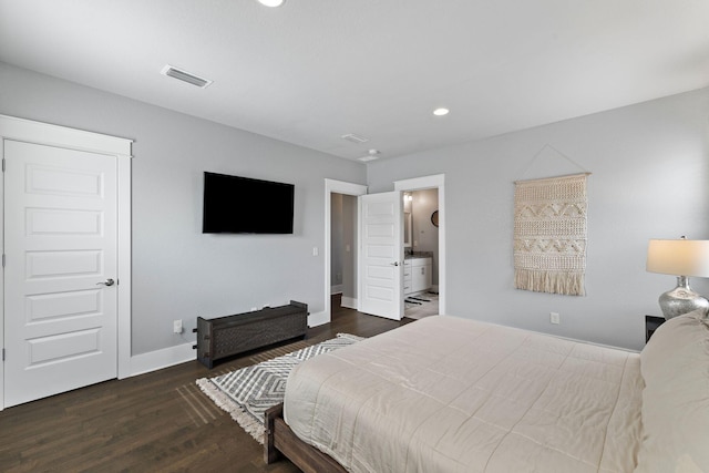 bedroom with ensuite bath and dark wood-type flooring