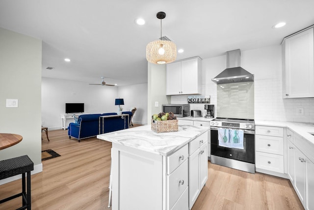 kitchen featuring wall chimney exhaust hood, a center island, appliances with stainless steel finishes, light hardwood / wood-style floors, and white cabinets