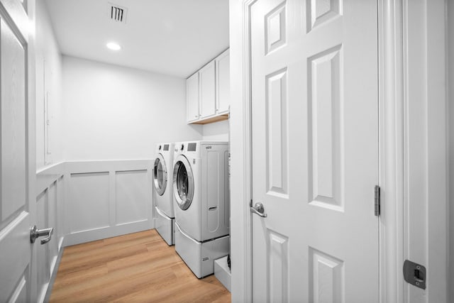 laundry room featuring light hardwood / wood-style floors, cabinets, and washing machine and clothes dryer