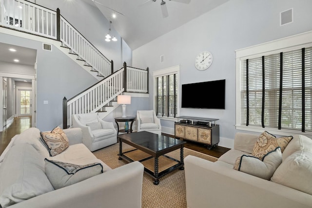 living room featuring hardwood / wood-style flooring, ceiling fan, and a high ceiling