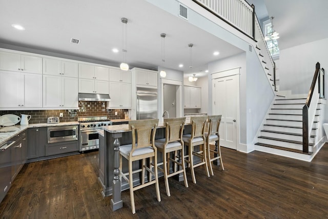 kitchen featuring white cabinetry, built in appliances, decorative light fixtures, and a kitchen island