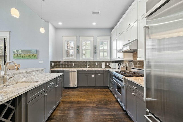 kitchen featuring sink, high end appliances, white cabinetry, decorative light fixtures, and dark hardwood / wood-style flooring