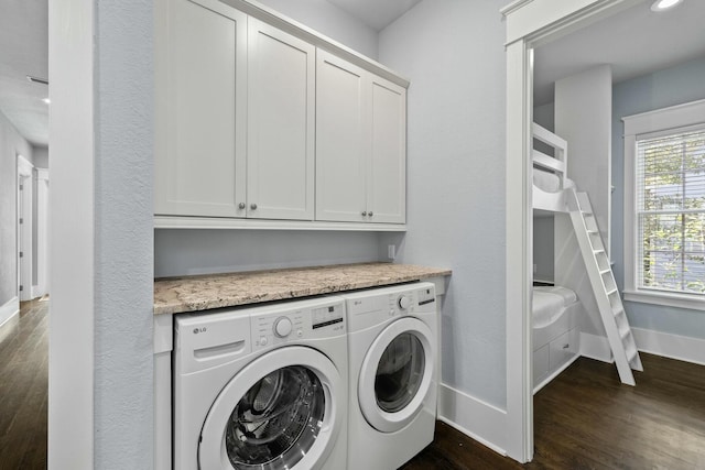 laundry area with dark wood-type flooring, washer and clothes dryer, and cabinets