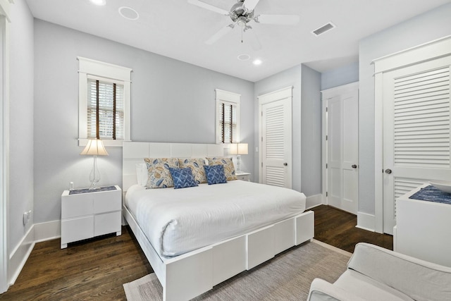 bedroom featuring dark hardwood / wood-style flooring, two closets, and ceiling fan