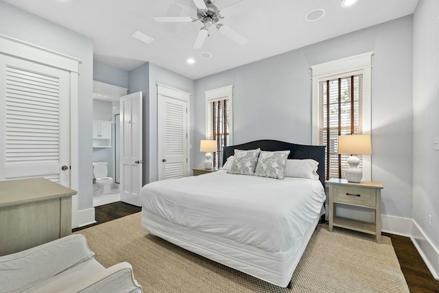 bedroom featuring dark wood-type flooring, ensuite bath, multiple closets, and ceiling fan