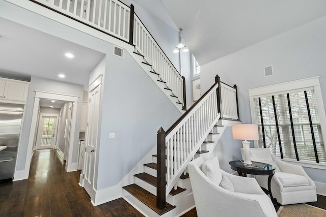 stairway with a towering ceiling and hardwood / wood-style floors