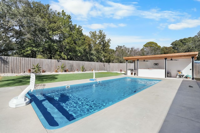 view of swimming pool featuring a patio, ceiling fan, and a lawn