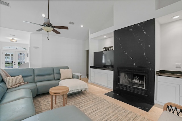 tiled living room featuring ceiling fan, lofted ceiling, a fireplace, and french doors