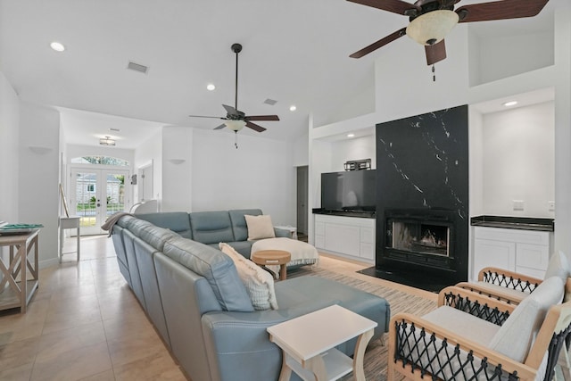 tiled living room with ceiling fan, high vaulted ceiling, a fireplace, and french doors