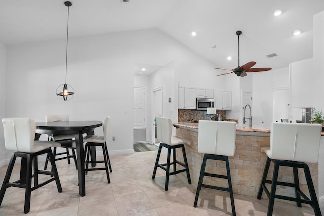 kitchen with white cabinetry, tasteful backsplash, hanging light fixtures, a kitchen breakfast bar, and kitchen peninsula