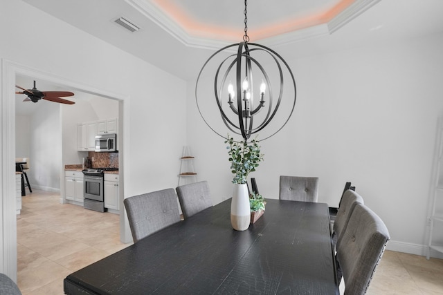 dining area with a raised ceiling, ceiling fan with notable chandelier, and light tile patterned floors