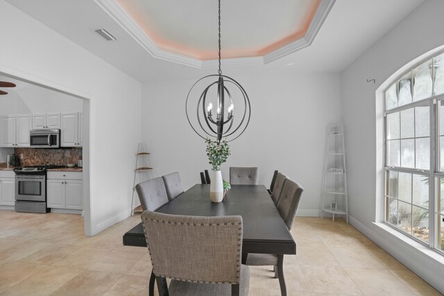 dining room with a raised ceiling, crown molding, a healthy amount of sunlight, and an inviting chandelier