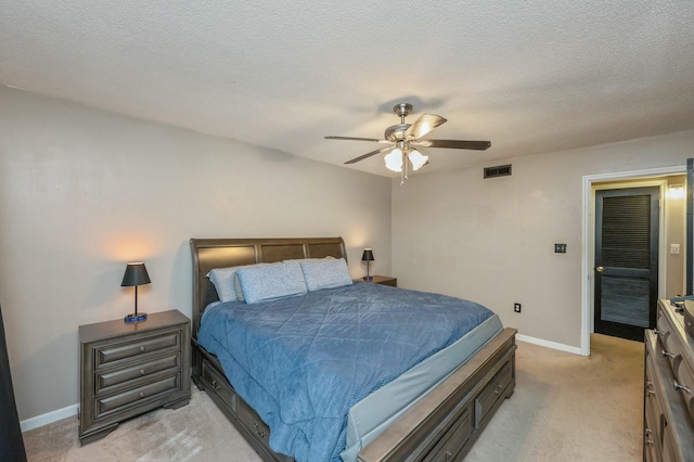 carpeted bedroom featuring ceiling fan and a textured ceiling