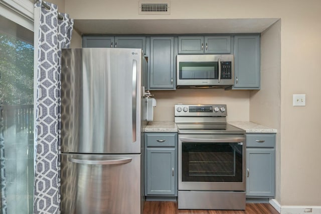 kitchen featuring appliances with stainless steel finishes, dark hardwood / wood-style floors, and gray cabinets