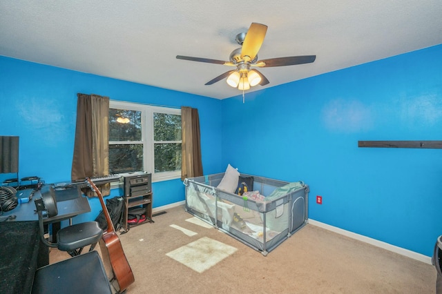 bedroom featuring light colored carpet, a textured ceiling, and ceiling fan