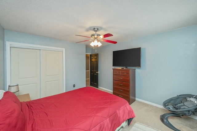 bedroom with ceiling fan, light colored carpet, a closet, and a textured ceiling