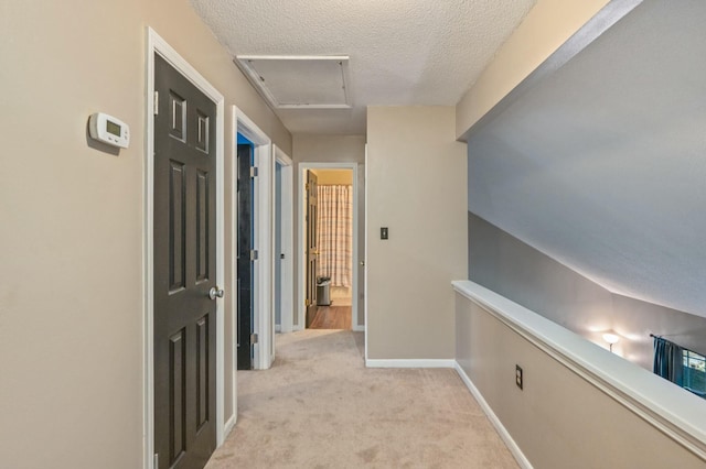 corridor with light colored carpet and a textured ceiling