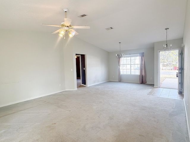 carpeted empty room featuring vaulted ceiling and ceiling fan with notable chandelier