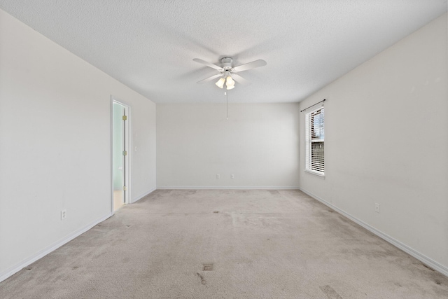 empty room with ceiling fan, light carpet, and a textured ceiling