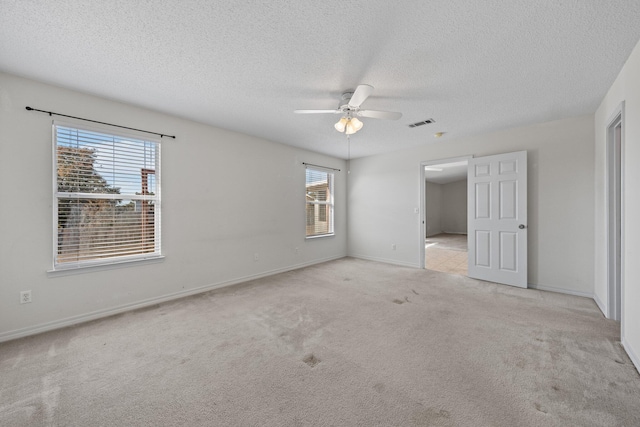 spare room with light colored carpet, a textured ceiling, and ceiling fan