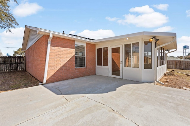 back of house featuring a sunroom, a patio, and solar panels