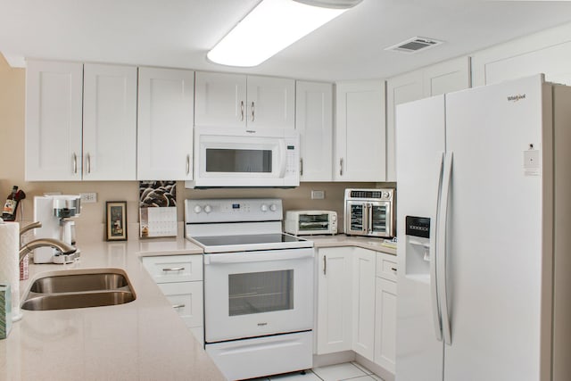 kitchen with white cabinetry, sink, white appliances, and light tile patterned floors