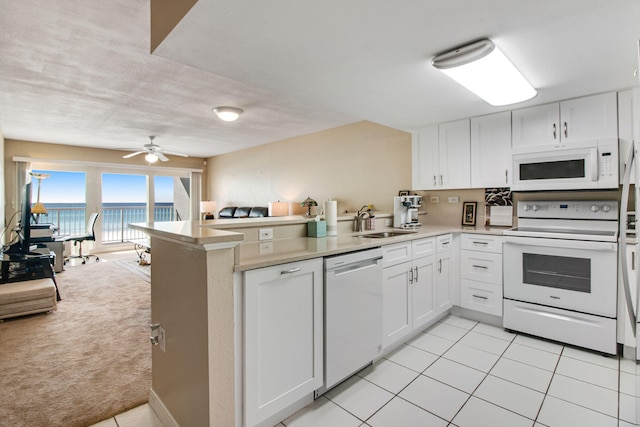 kitchen with white cabinetry, a water view, light colored carpet, and white appliances