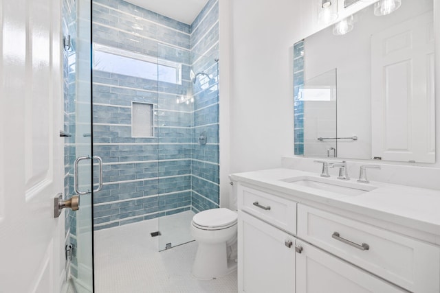 bathroom with toilet, vanity, tile patterned floors, and a shower with shower door