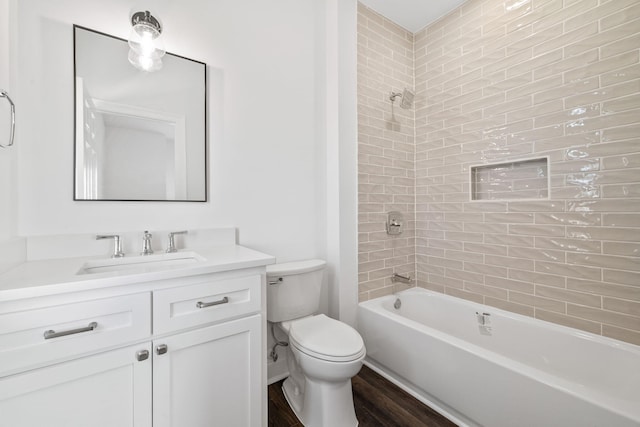 full bathroom with tiled shower / bath combo, vanity, hardwood / wood-style flooring, and toilet