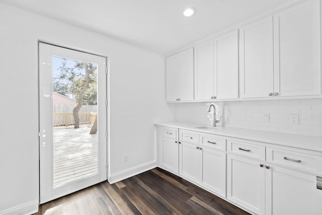 interior space with backsplash, sink, and white cabinets