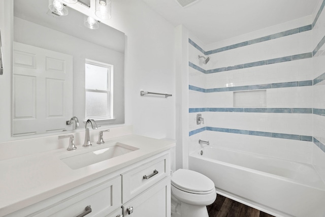 full bathroom featuring wood-type flooring, tiled shower / bath, vanity, and toilet