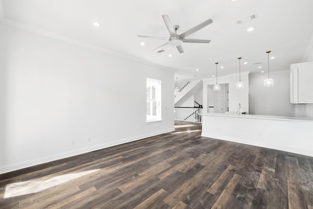 unfurnished living room featuring dark wood-type flooring, ornamental molding, and ceiling fan