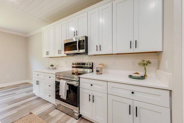 kitchen featuring white cabinetry, ornamental molding, stainless steel appliances, and light wood-type flooring