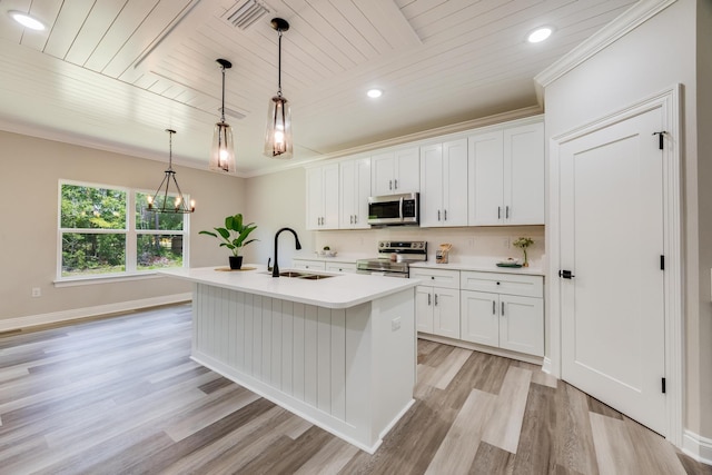 kitchen featuring sink, appliances with stainless steel finishes, white cabinetry, hanging light fixtures, and a center island with sink