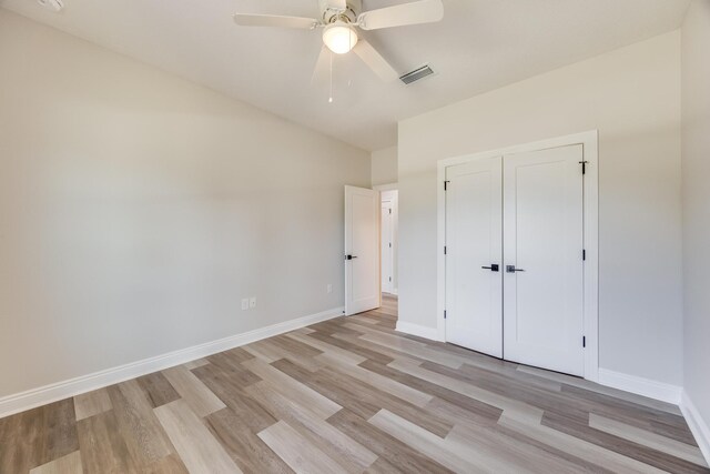 unfurnished bedroom with light hardwood / wood-style flooring, a closet, and ceiling fan