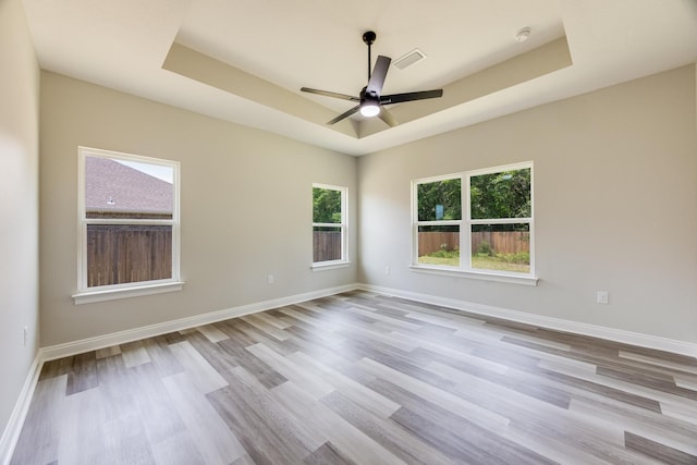 unfurnished room featuring light hardwood / wood-style flooring, ceiling fan, and a tray ceiling