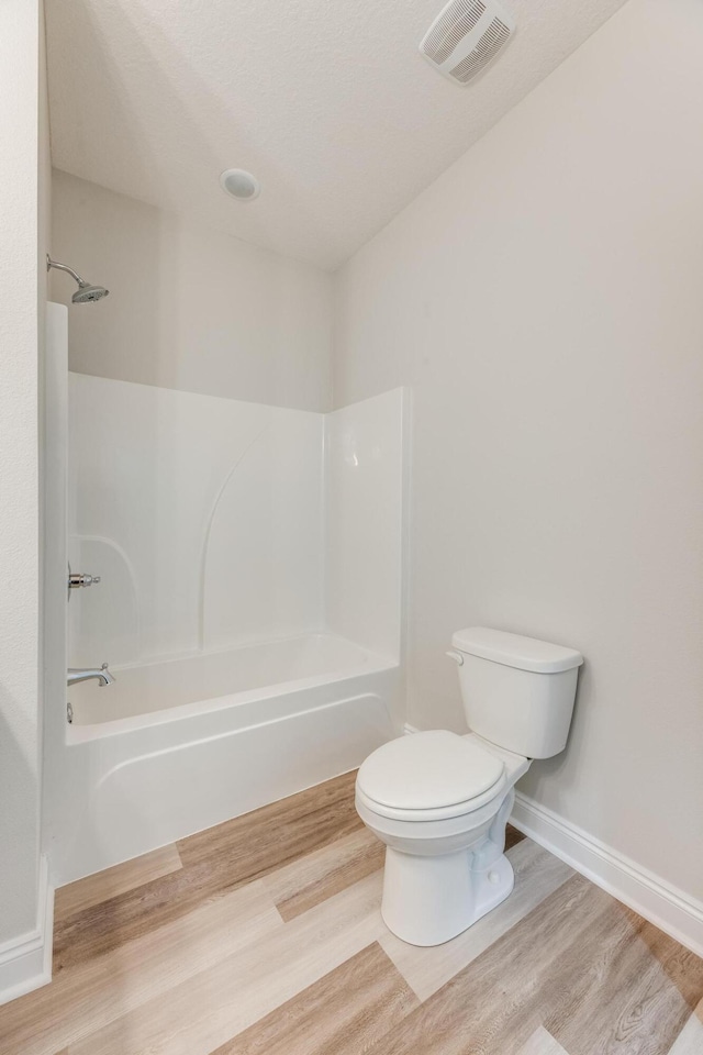 bathroom featuring toilet, bathing tub / shower combination, and hardwood / wood-style floors