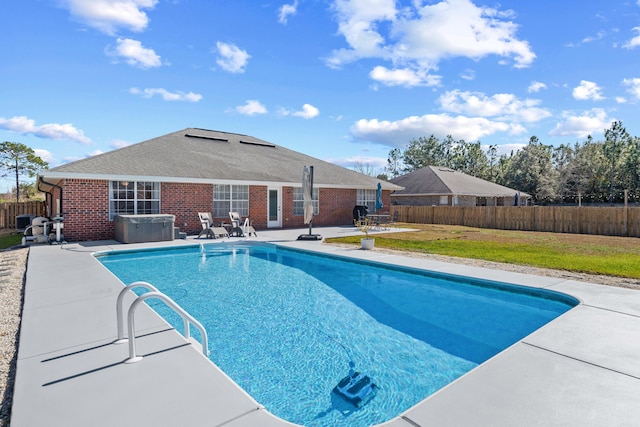 view of swimming pool featuring a lawn, a hot tub, and a patio