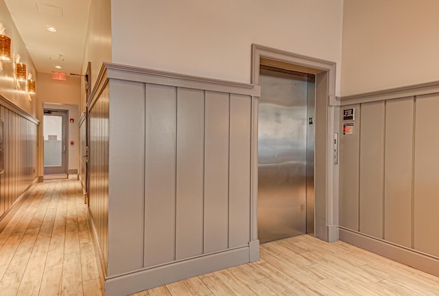 hall with elevator and light hardwood / wood-style floors