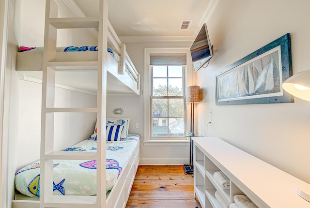 bedroom featuring multiple windows, ornamental molding, and light wood-type flooring