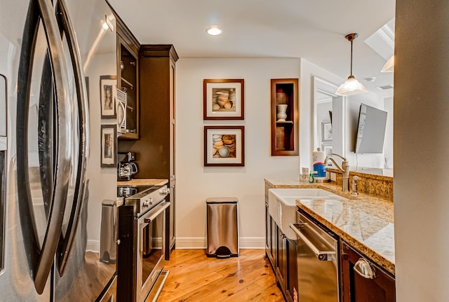 kitchen with decorative light fixtures, sink, stainless steel appliances, light stone countertops, and dark brown cabinets