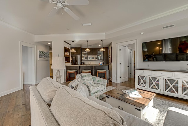 living room with hardwood / wood-style flooring, ornamental molding, and ceiling fan