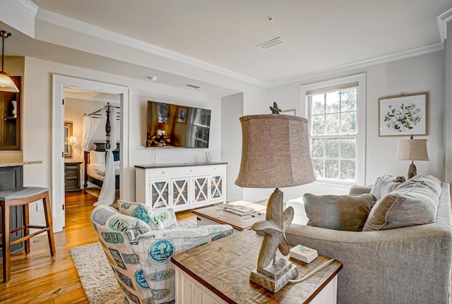 living room with ornamental molding and light hardwood / wood-style floors