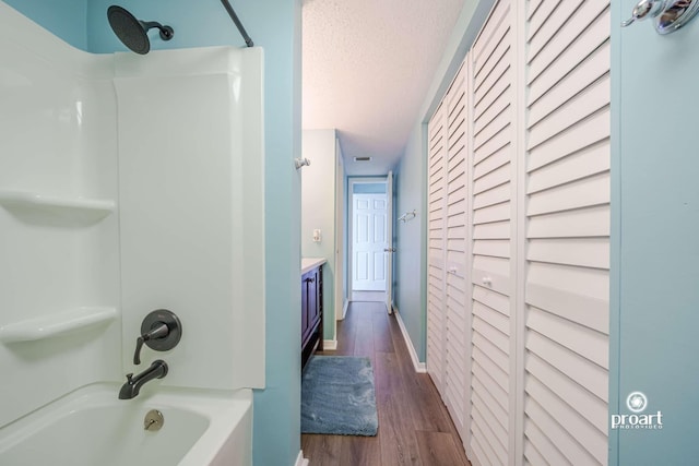 bathroom with vanity, hardwood / wood-style floors, bathing tub / shower combination, and a textured ceiling