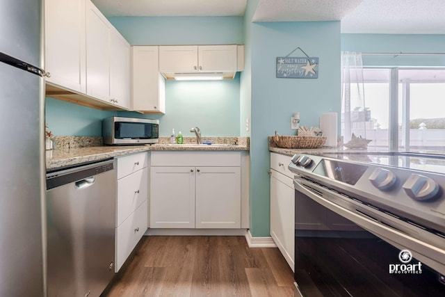 kitchen with white cabinetry, appliances with stainless steel finishes, sink, and wood-type flooring