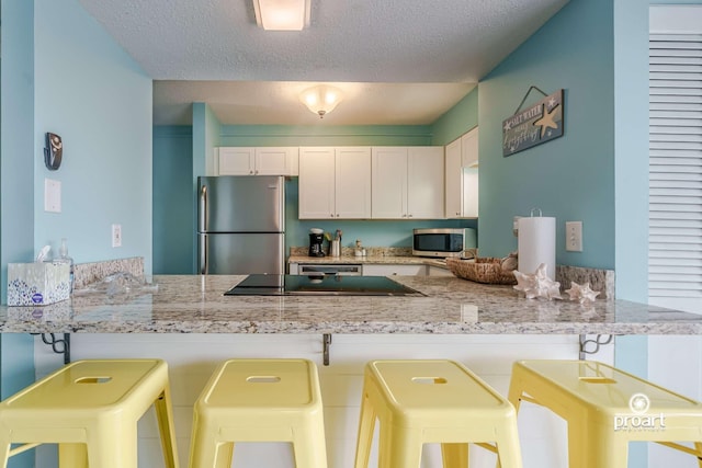 kitchen featuring appliances with stainless steel finishes, a kitchen breakfast bar, and kitchen peninsula